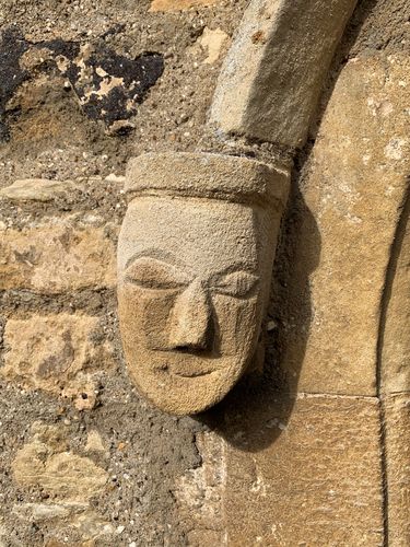 A limestone face carving known as a head stop on the south side of the nave of St Michael's Church, Walton. Construction of the nave dates from c.1340 although there was a church on site from the 12th Century. Photographed in 2022.  